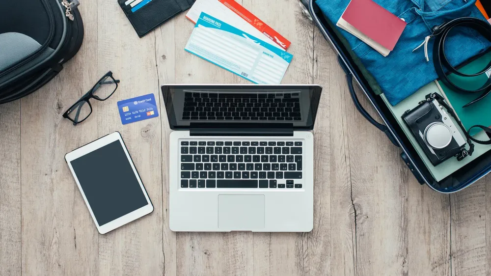 Traveler packing and getting ready for a trip, desktop with baggage, tickets, credit card, laptop and digital tablet, flat lay